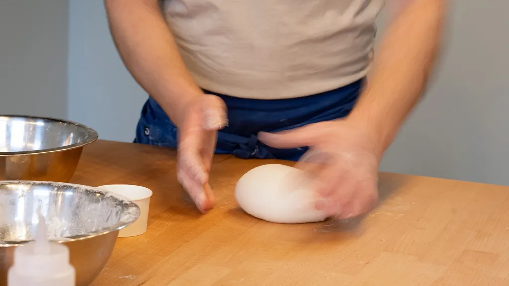 Close-up of a person kneading pizza dough on a wooden table during a workshop at ALBA Zurich — featured by BYCA Zurich.