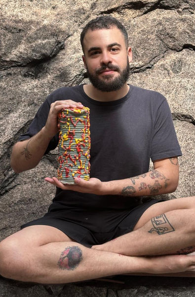 Foto do artista Jean Viveiros segurando sua obra, escultura em cerâmica e esmaltes de alta temperatura 