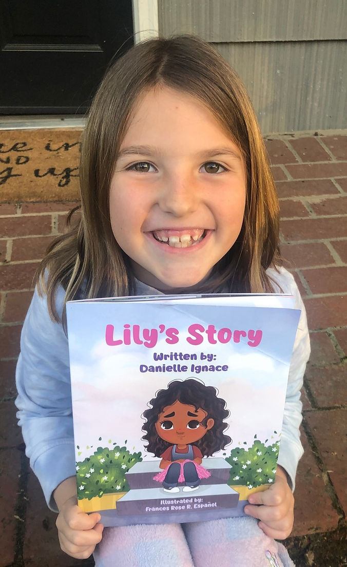 A little girl holding a copy of the book Lily's Story