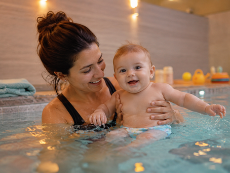 baby zwemt onder begleiding in het zwembad