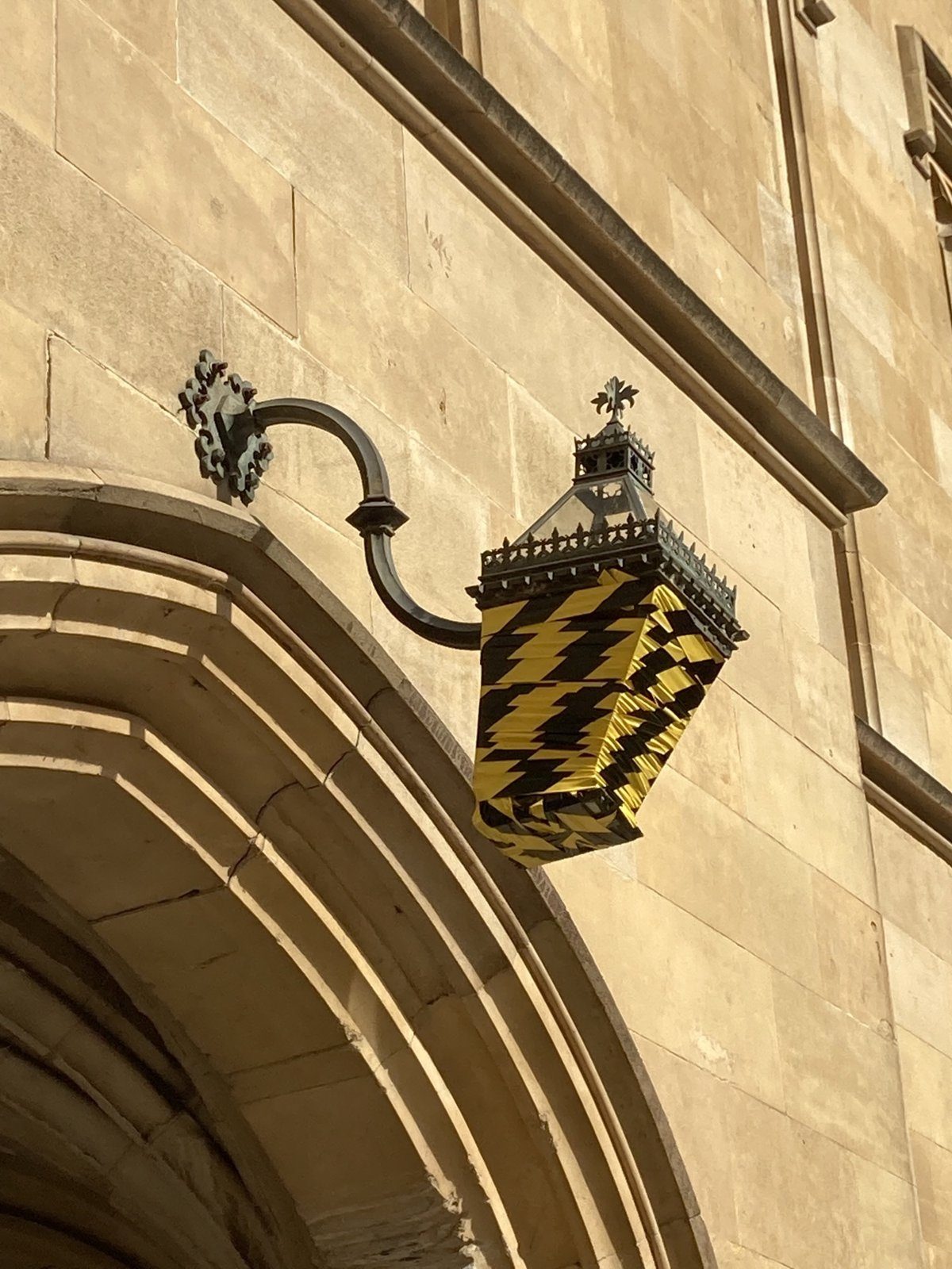 Damaged Gothic lantern on its bracket, covered in tape before removal