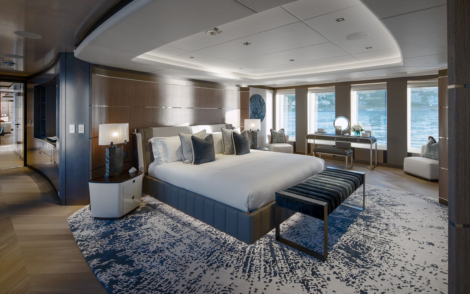 Owner's suite on a yacht with a panelled headboard wall, table lamps and sea views