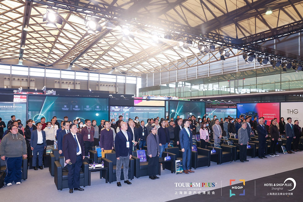 People standing in a spacious conference hall at Shanghai New International Expo Center with a geometric ceiling, looking forward. Colorful banners display text. Mood is attentive.