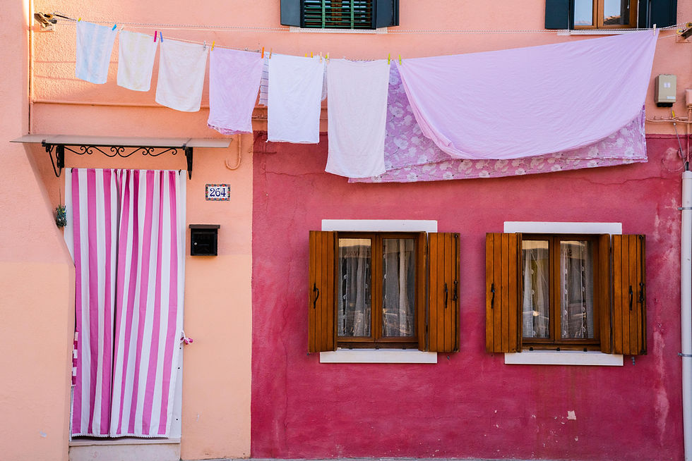 Photographie d’art d’une façade colorée de Burano avec linge suspendu et volets en bois.