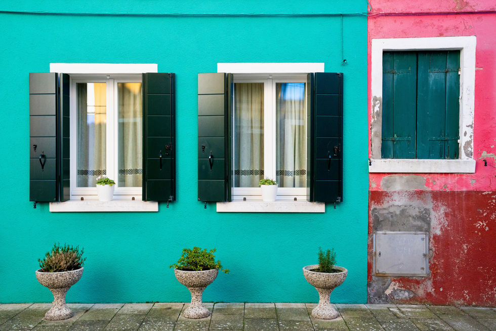 Photographie d’une façade turquoise et rose à Burano, contrastant entre fraîcheur et usure du temps