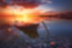 Barque et paysage de l'étang de Pérols au coucher du soleil, avec des nuances de rose et d'orange en Occitanie