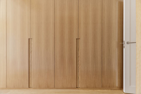 Frontal image of a bedroom hallway covered with built-in light oak wood cabinets .jpg