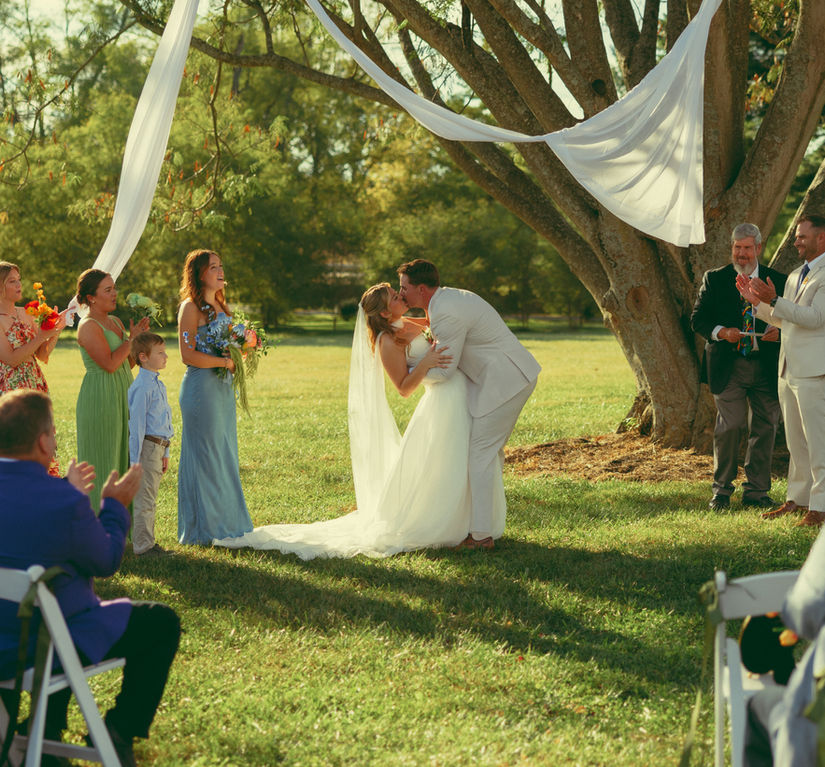 wedding ceremony with couple under a tree embracing
