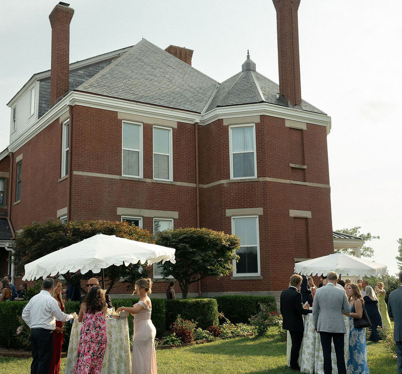 old brick house with couples, cocktail tables and umbrellas
