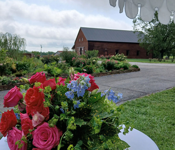 flowers on table with reception hall barn in the background