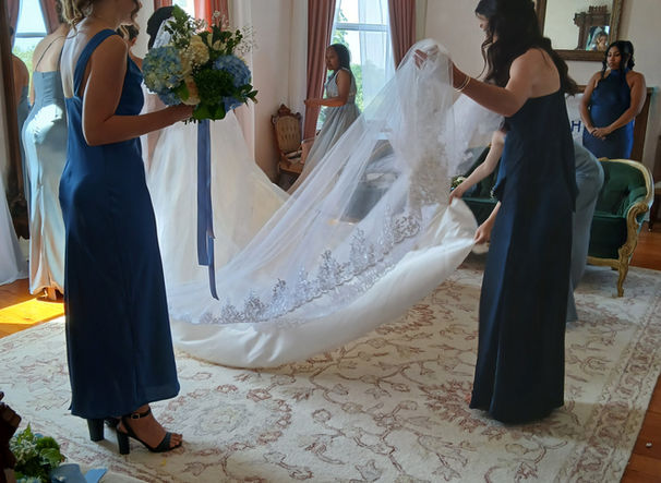 Bridesmaids fixing the veil before a wedding ceremony, in a bright room.
