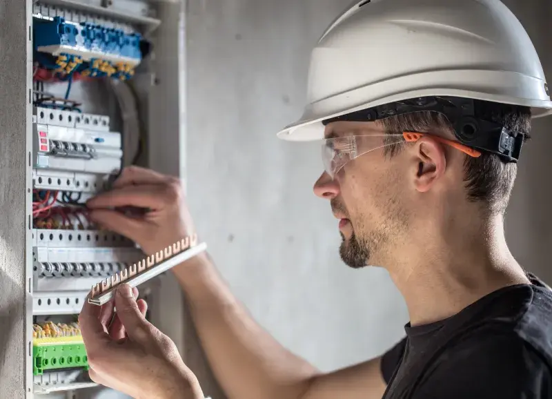 Electrician in hard hat installing a commercial fuse box