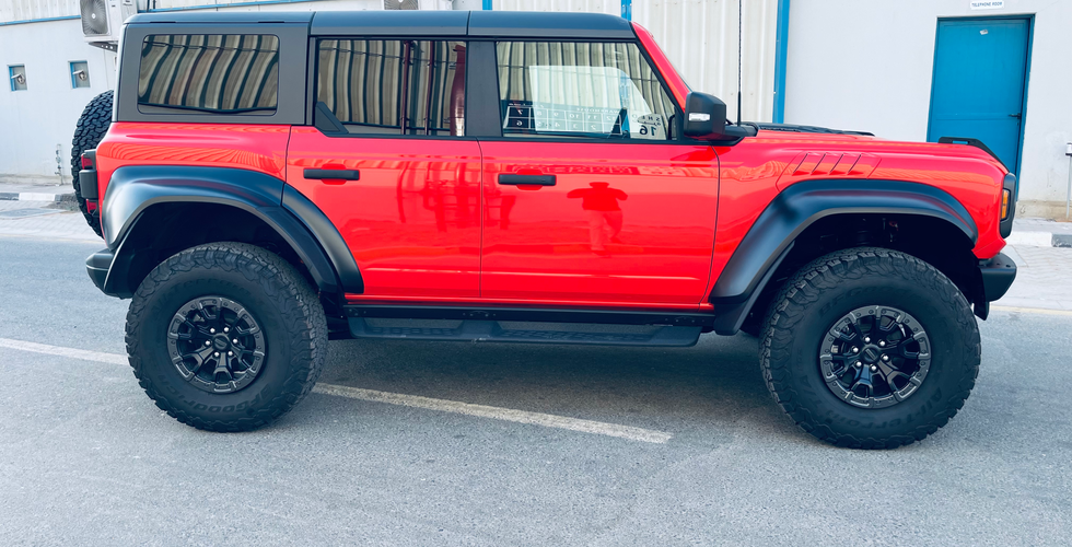 Side view of RHD Ford Bronco Raptor wildtrack pick-up with a striking red exterior and black alloys and detaling