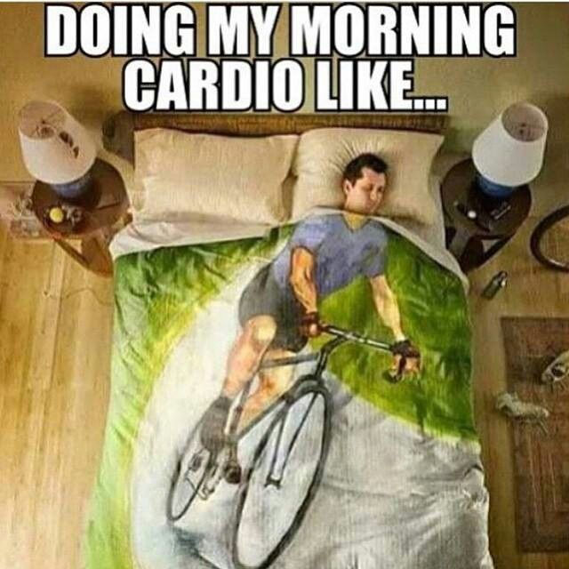 The words "doing my morning cardio like..." are at the top. Underneath them is a picture of a person sleeping under covers with a print of someone biking. The person's head is directly aligned with the body of the biker.