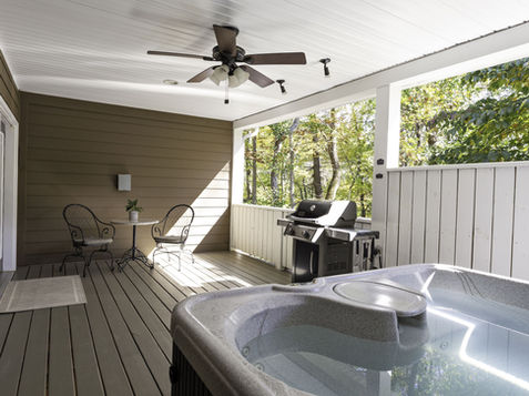 Outdoor patio with hot tub, grill, table, chairs and a ceiling fan