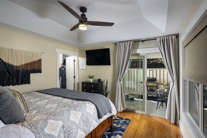 Cozy bedroom with bed, TV, and open sliding door to outdoor patio.