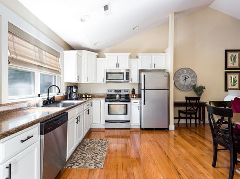White kitchen with stainless steel appliances and hardwood floors.