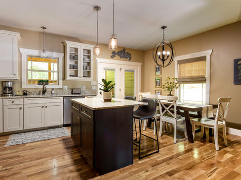 Modern kitchen with white cabinets, island, and dining area featuring 