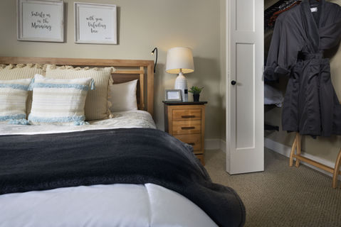 Bedroom with bed, pillows, nightstand, robe, and framed art on the wall.