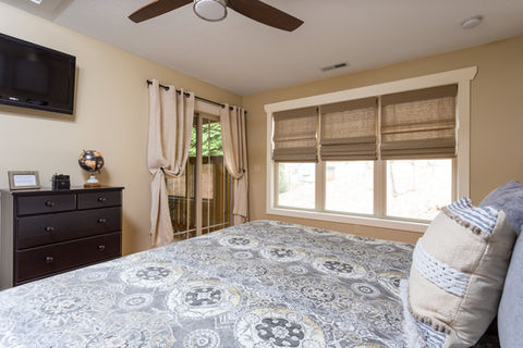 Bedroom with a bed, dresser, window, and television. Asheville Cottages New Site.