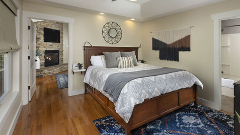 Bedroom with bed, rug, mirror and an open door to a fireplace or bathroom.