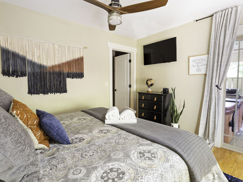 Bedroom with bed, pillows, TV, closet, and a view of the outside Asheville Cottages New Site