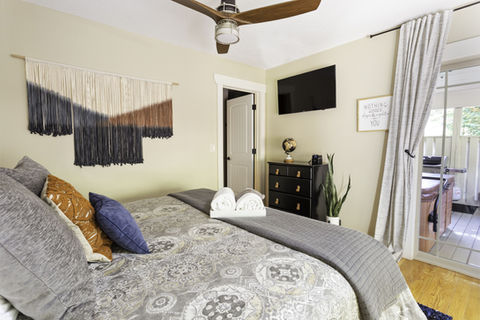 Bedroom with bed, pillows, TV, closet, and a view of the outside Asheville Cottages New Site