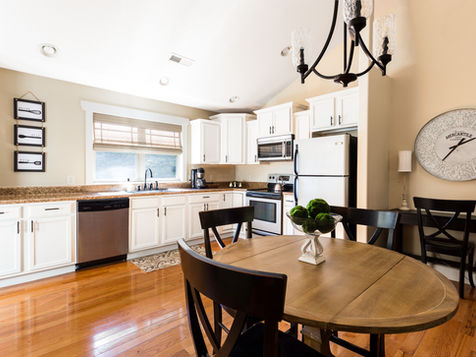 Bright kitchen with white cabinets, round table and chairs, and window Asheville Cottages New Site