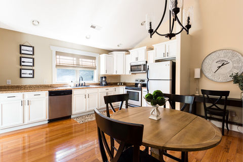 Bright kitchen with white cabinets, round table and chairs, and window Asheville Cottages New Site