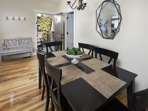 Dining room with black table and chairs, hardwood floor, and a mirror.