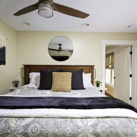 Cozy bedroom with bed, pillows, mirror, window, a fan and decor Asheville Cottages New Site