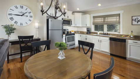 Cozy kitchen with a round table, clock, and white cabinets for cooking.
