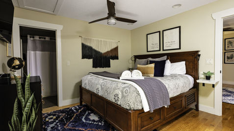 Bedroom with bed, art, rug, and bathroom visible. Asheville Cottages New Site.