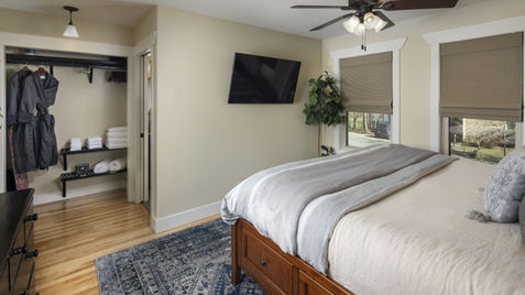 Bedroom with bed, TV, closet, and rug; neutral colors, modern design.