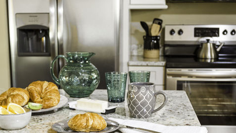 Breakfast on kitchen island with croissants and drinks; stainless steel appliances. Asheville Cottages New Site