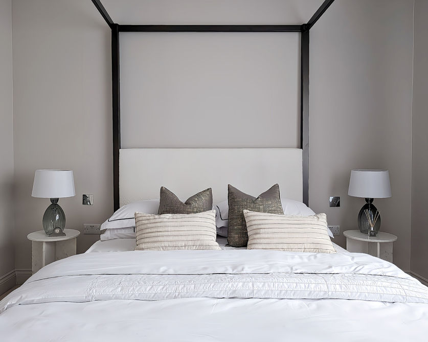 Four-poster bed with layered neutral bedding in staged London bedroom.