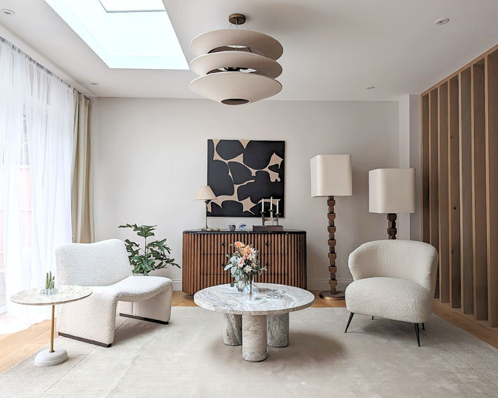 London home staging living room with boucle chairs, ribbed wood sideboard, abstract art, and marble coffee table.