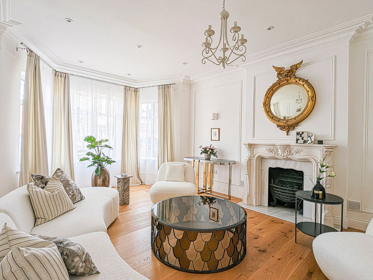 London home staging period formal reception room with fireplace, neutral sofa, and statement coffee table.