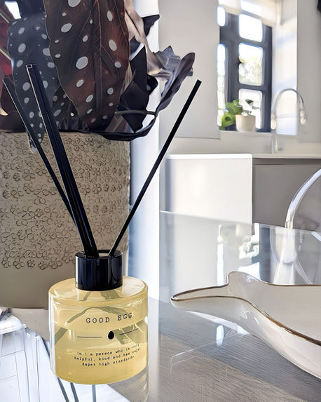 Close-up of a reed diffuser placed beside a sink area, highlighting reflective surfaces and modern kitchen finishes.
