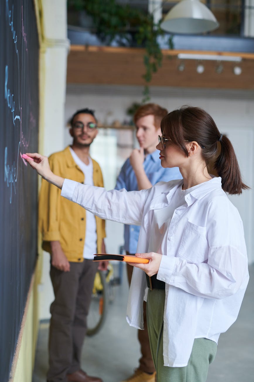 photo of woman writing on blackboard