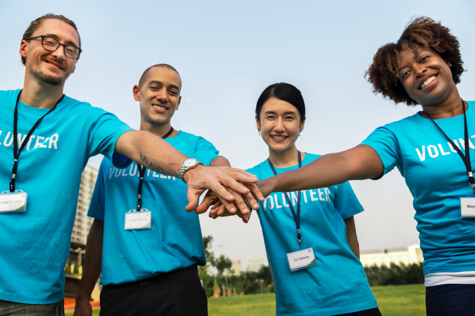men and women combining hands together while smiling