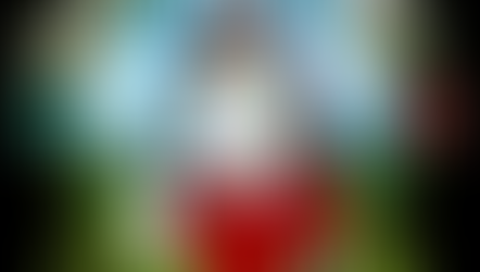 A cheerful circular Raised By Rangers FFYO emblem featuring a smiling white unicorn with rainbow-colored mane and horn, holding a phone to its ear. The unicorn wears a red shirt and stands before a bright mountain landscape with blue skies and flowers on each side. The words “CONTACT US” appear boldly at the bottom in green letters.