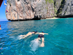 Travelers snorkeling in clear turquoise water at Phi Phi Islands on a private longtail boat tour