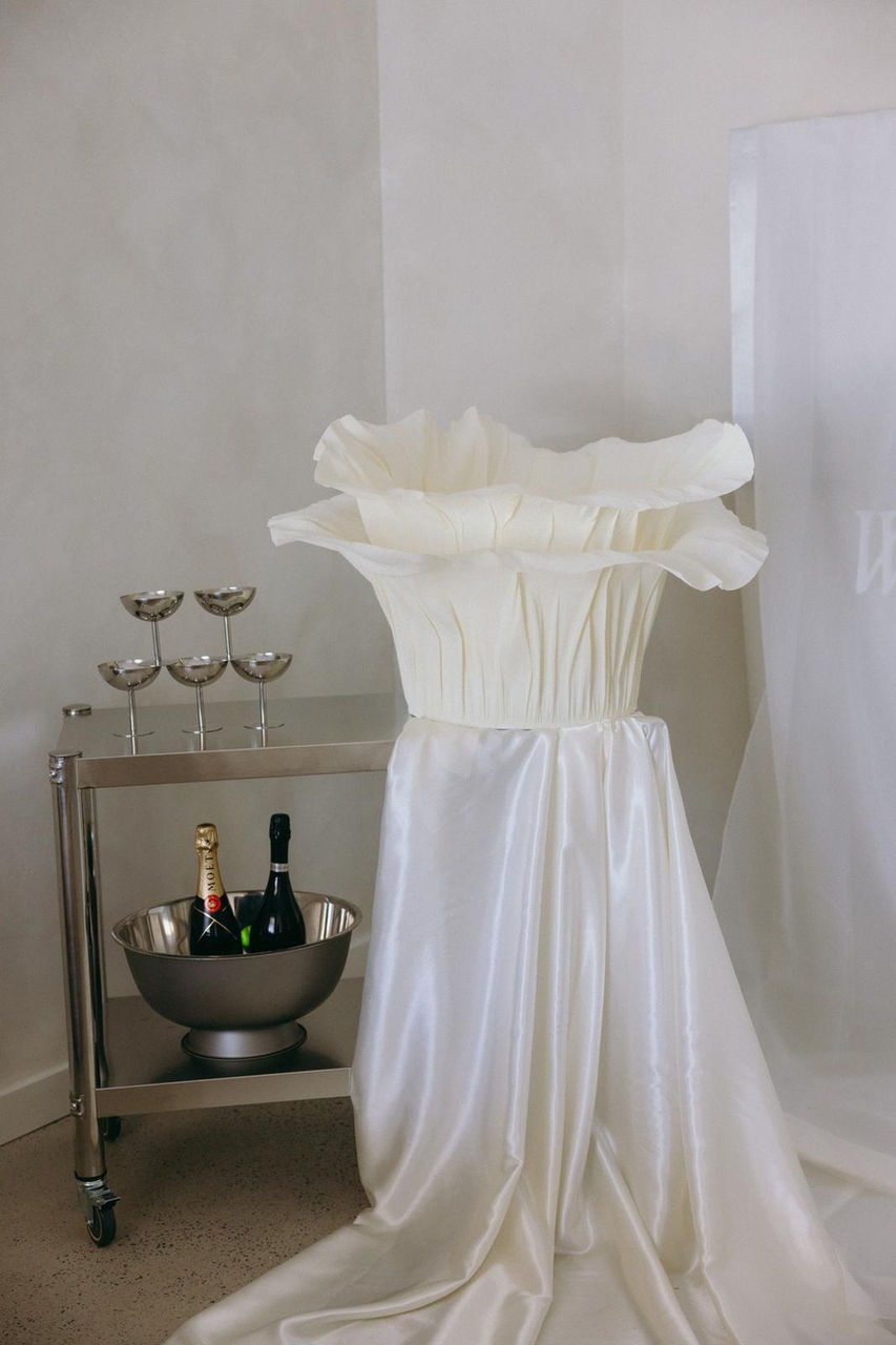 Full-length Bloom Wishing Well dressed in satin, styled beside a champagne bar cart for a luxury reception moment.