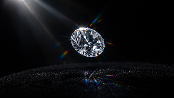 Diamond suspended mid air with light beam scattering into rainbow flares