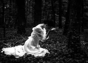 Femme en robe blanche agenouillée en forêt sombre, penchée sur une fleur, ambiance silencieuse et rêveuse pour illustrer Circé de Madeline Miller