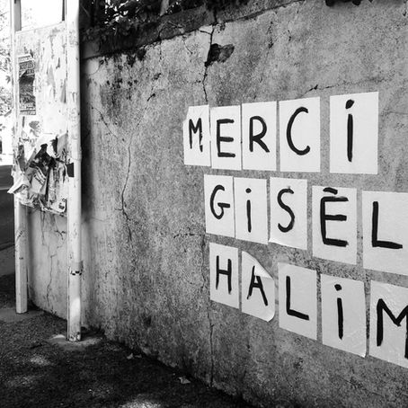 Un collage féministe en lettres noires sur un mur blanc urbain affichant le message : Merci Gisèle Halimi. Hommage à l'avocate et militante féministe.