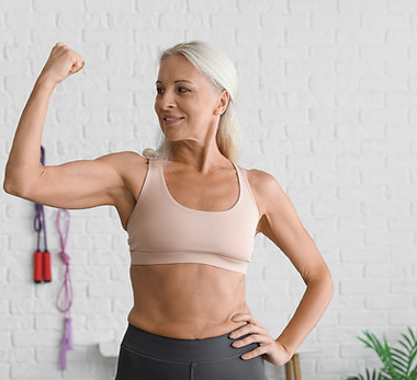 Body positive mature woman showing muscles in gym