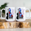 Thumbnail: Right Facing Abstract White 11 Ounce Piano Mug. Colorful Floral Design Screened Over Black Piano graphic. Cello on the Left of the Piano. Personalized with Recipient Name. Mug Sitting on a White Granite Table with succulents in the Background. 