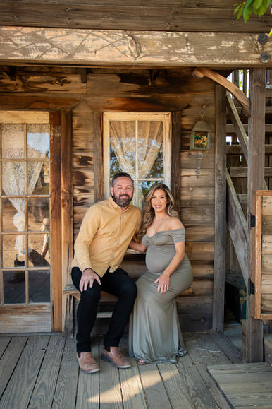 Pregnant couple sitting together on rustic wooden porch in Pioneertown maternity session near Joshua Tree